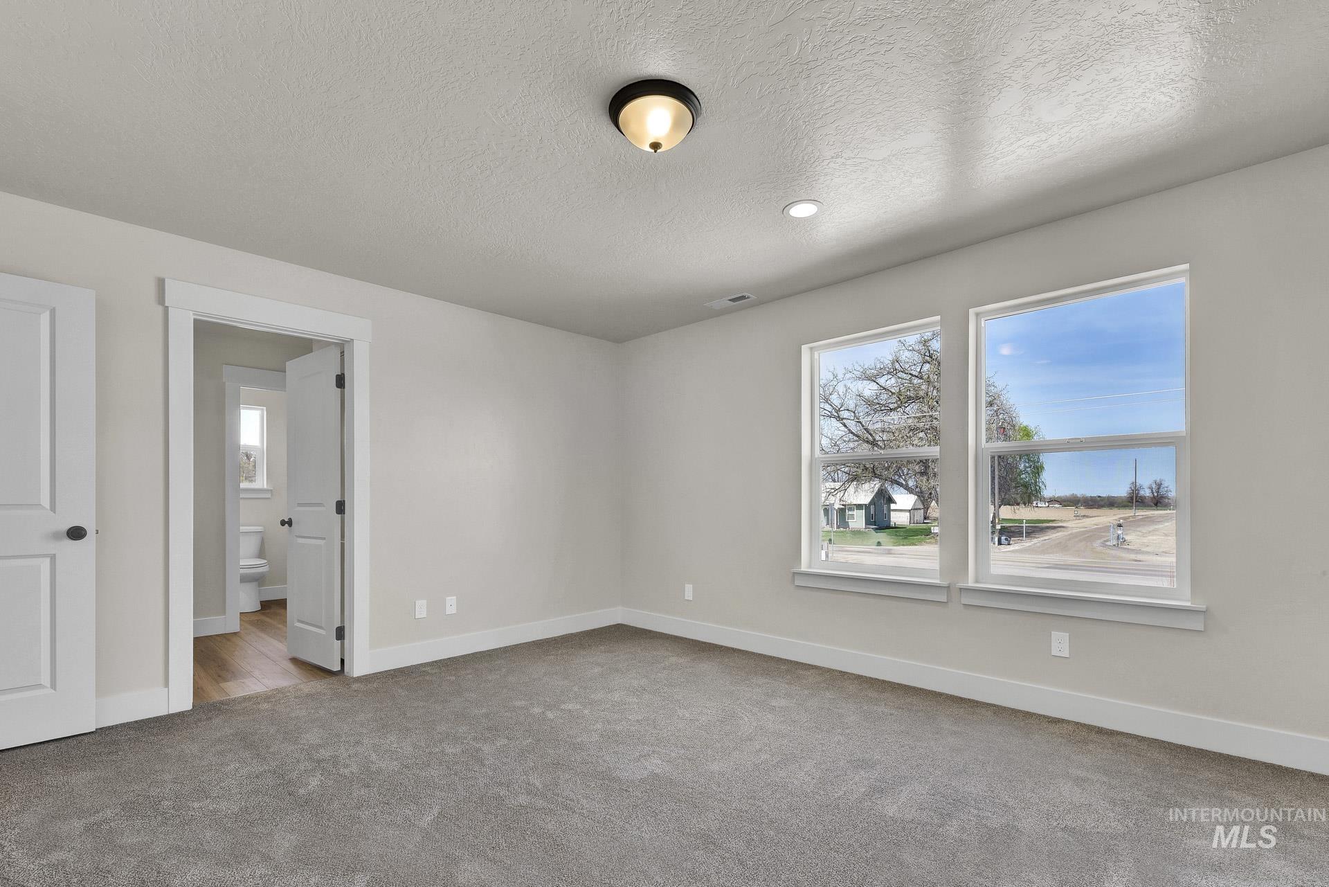 Unfurnished bedroom with light colored carpet and a textured ceiling