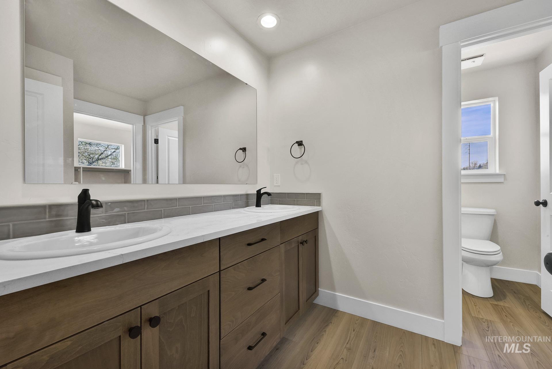 Bathroom with healthy amount of natural light, light wood-type flooring, double vanity, and recessed lighting