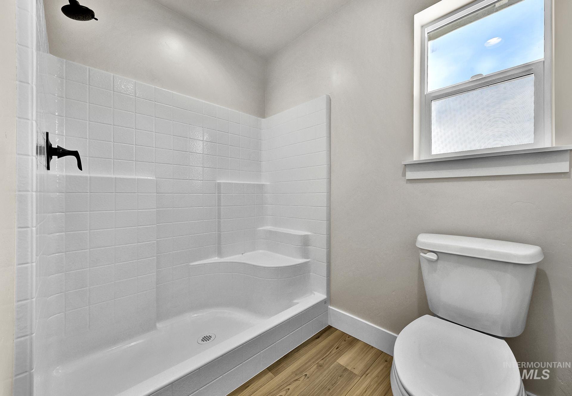 Bathroom with light wood-style flooring and tiled shower