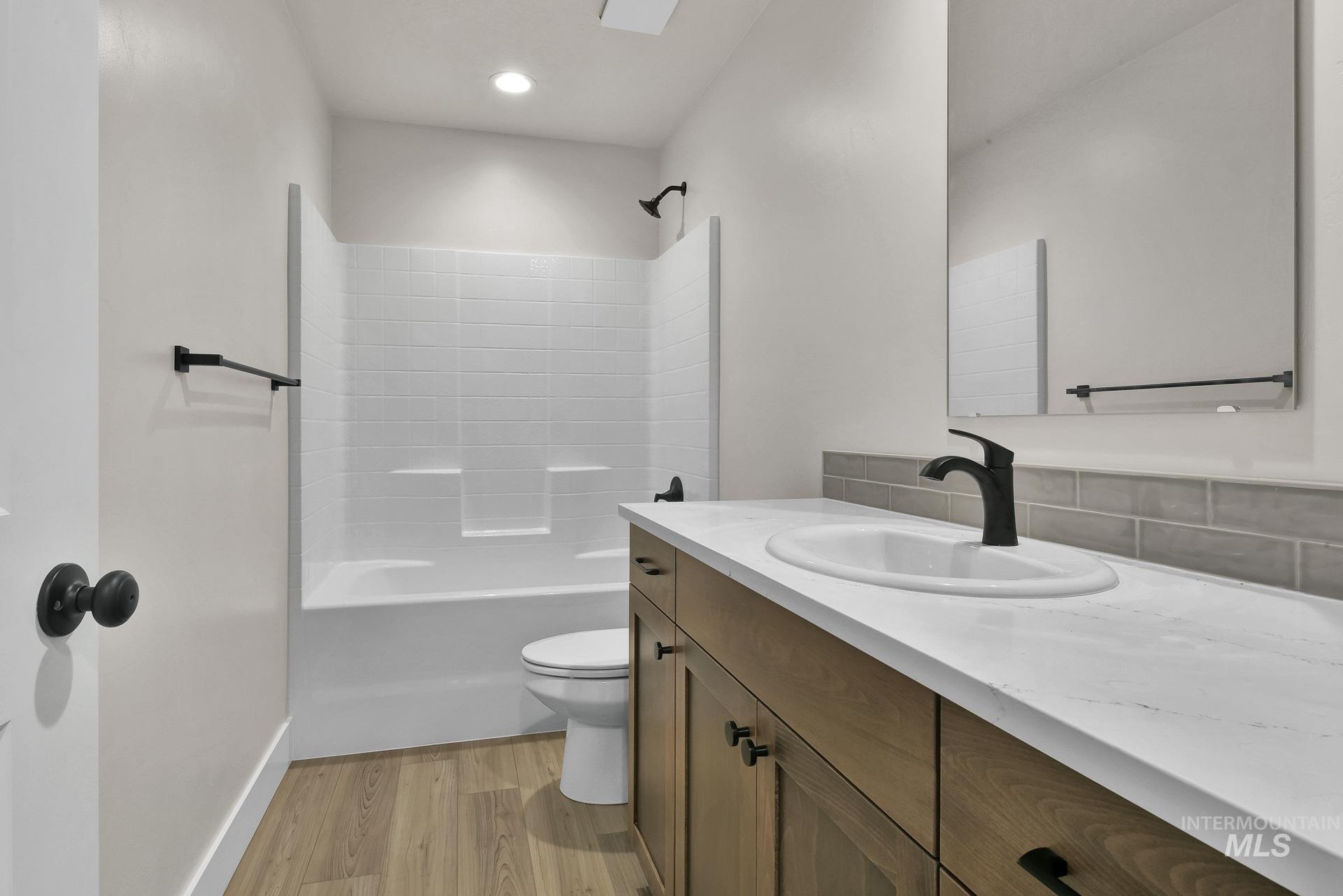 Bathroom with light wood-style flooring, vanity, shower / washtub combination, and recessed lighting