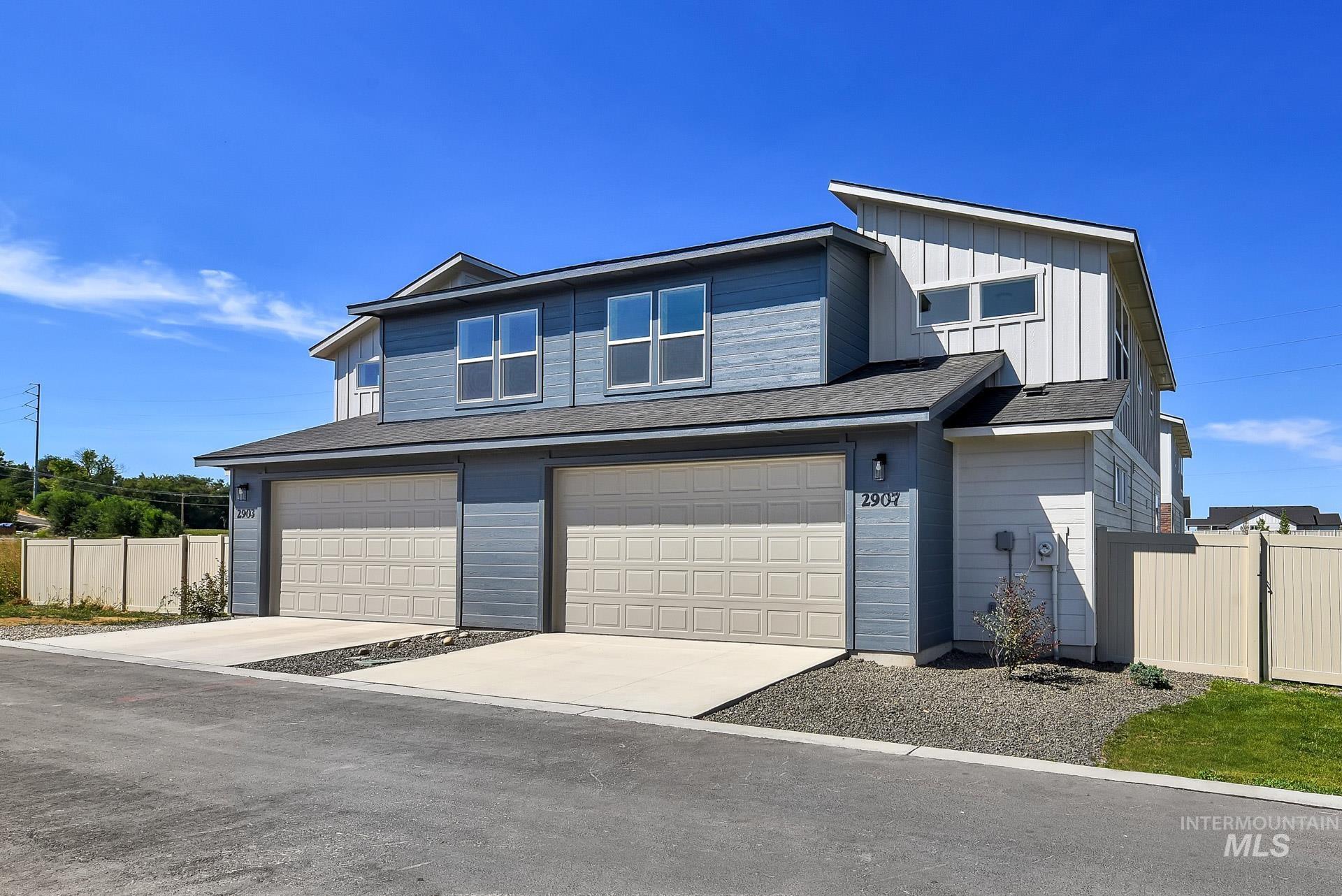 View of front of house with board and batten siding, an attached garage, concrete driveway, and a shingled roof