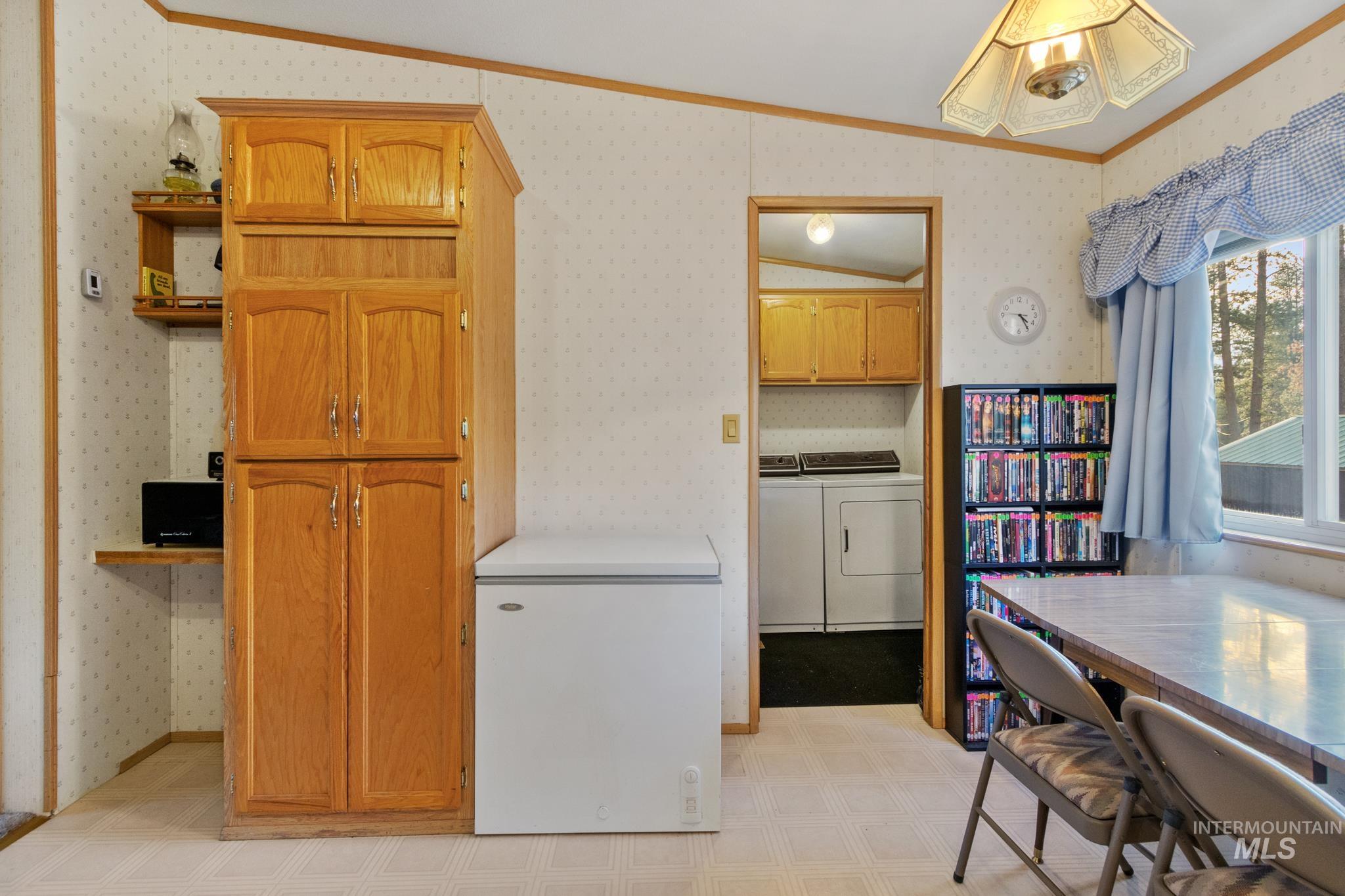 Kitchen with ornamental molding, wallpapered walls, light countertops, independent washer and dryer, and open shelves
