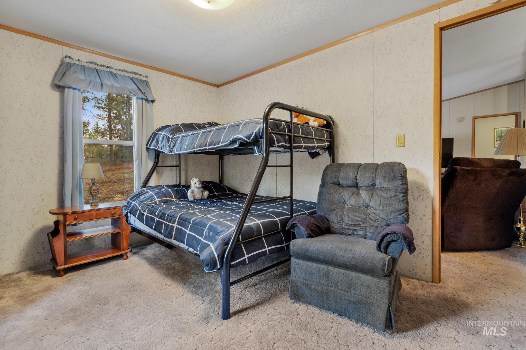 Bedroom featuring crown molding and wallpapered walls