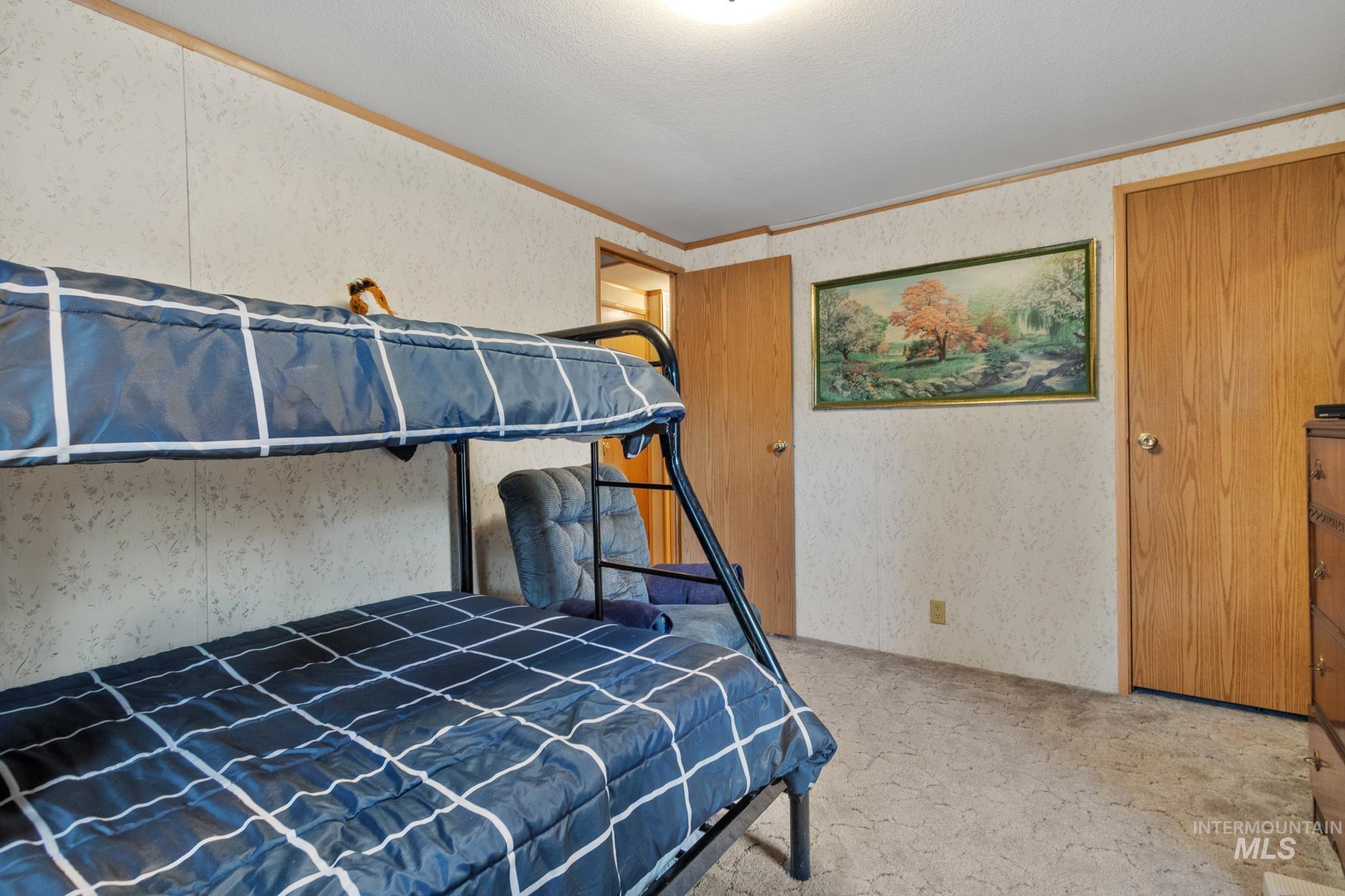Carpeted bedroom with wallpapered walls and crown molding