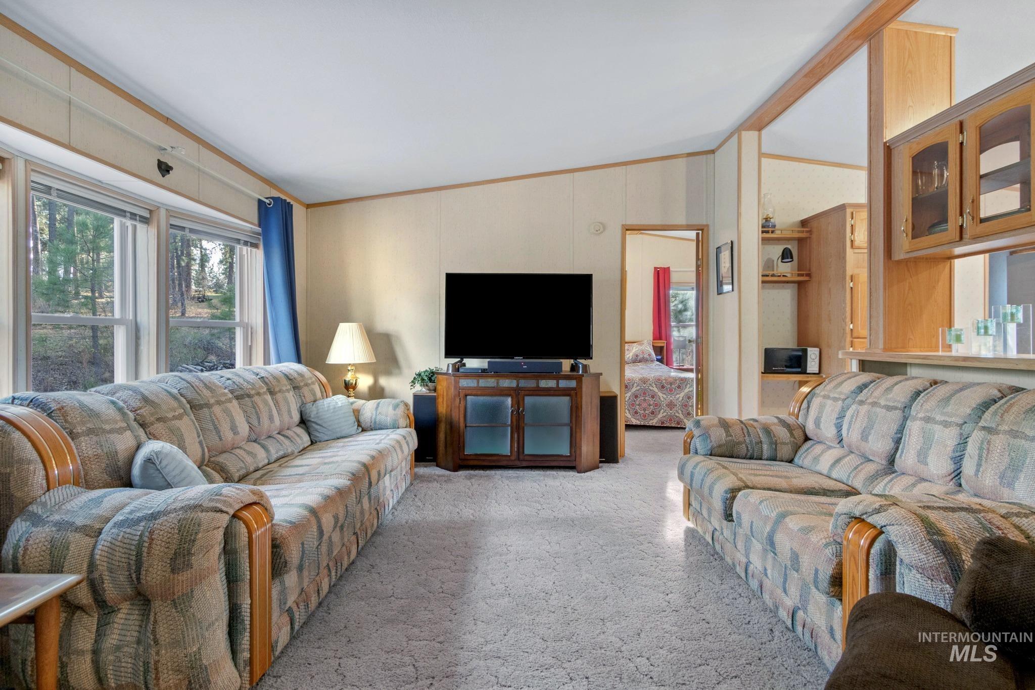 Carpeted living area featuring vaulted ceiling, healthy amount of natural light, and crown molding