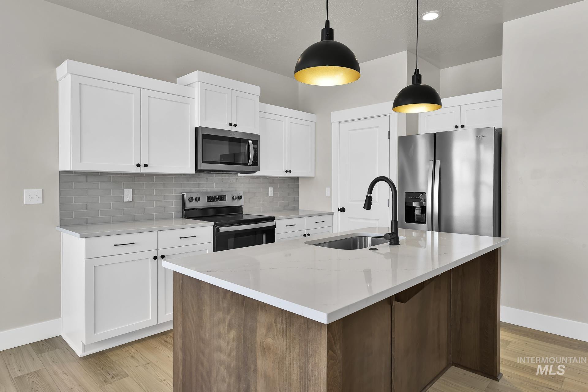 Kitchen featuring stainless steel appliances, an island with sink, backsplash, light stone counters, and recessed lighting