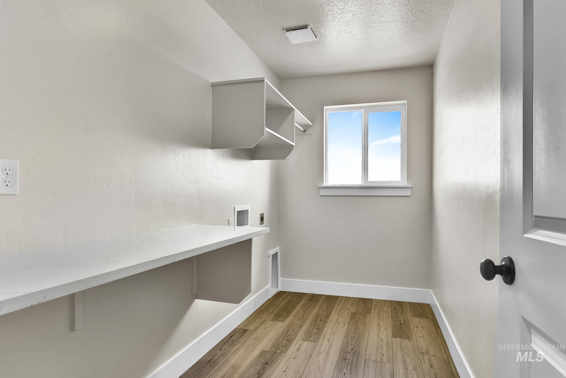 Laundry area featuring light wood-style floors, a textured ceiling, washer hookup, and electric dryer hookup
