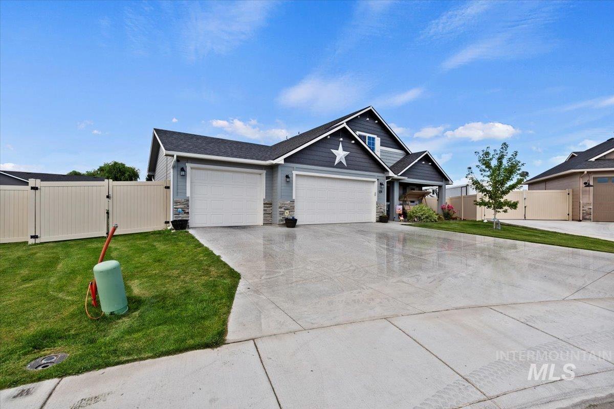 View of front of house with a gate, stone siding, a garage, and driveway