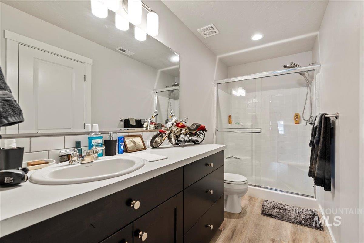 Full bathroom with wood finished floors, vanity, a shower stall, and tasteful backsplash