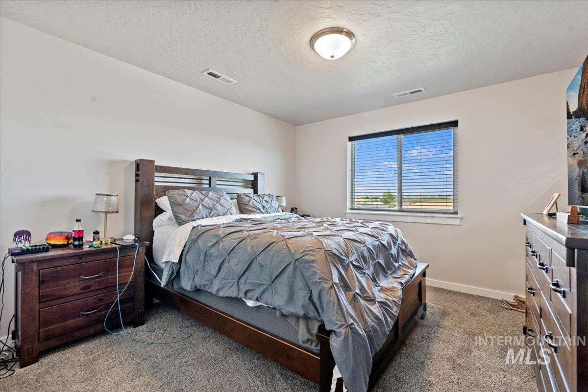 Carpeted bedroom with a textured ceiling and baseboards
