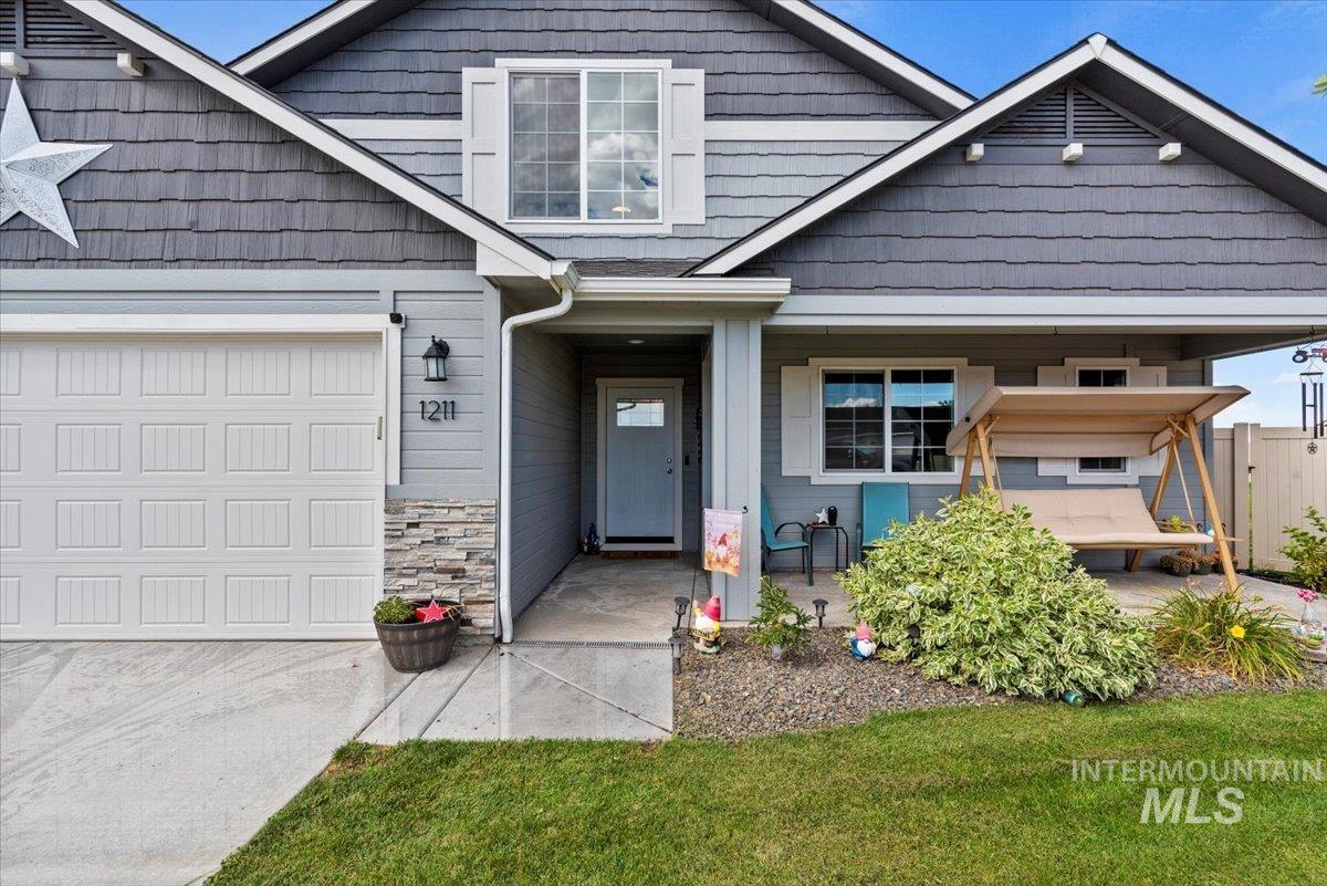 View of front of home with stone siding, an attached garage, and a porch
