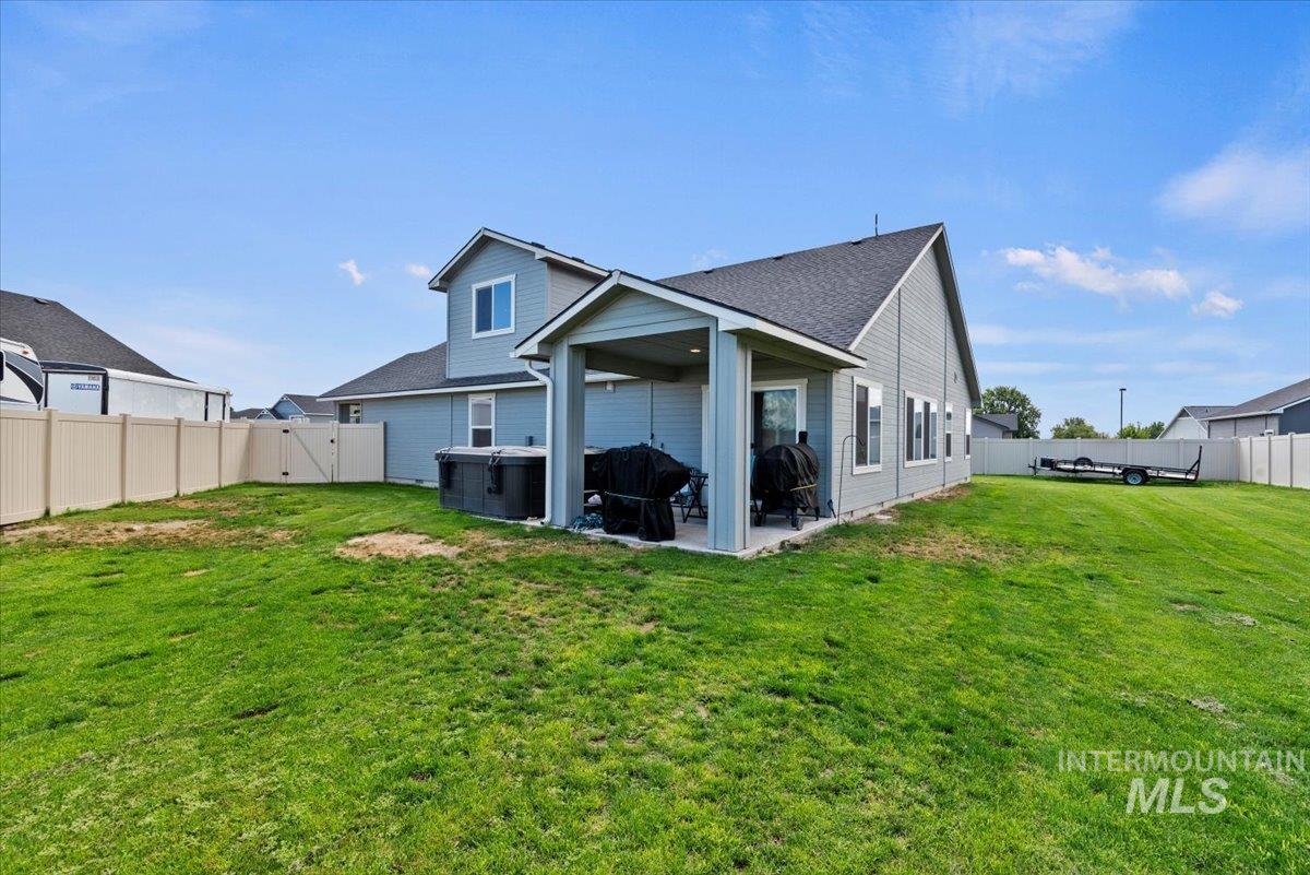 Rear view of property featuring a fenced backyard, a patio area, a hot tub, and a shingled roof