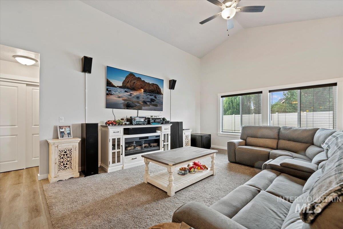 Living room featuring light wood finished floors, high vaulted ceiling, and ceiling fan