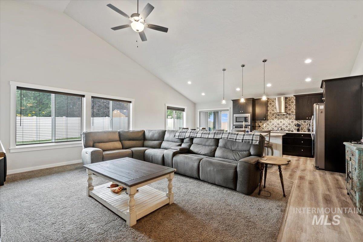 Living room featuring high vaulted ceiling, ceiling fan, and recessed lighting