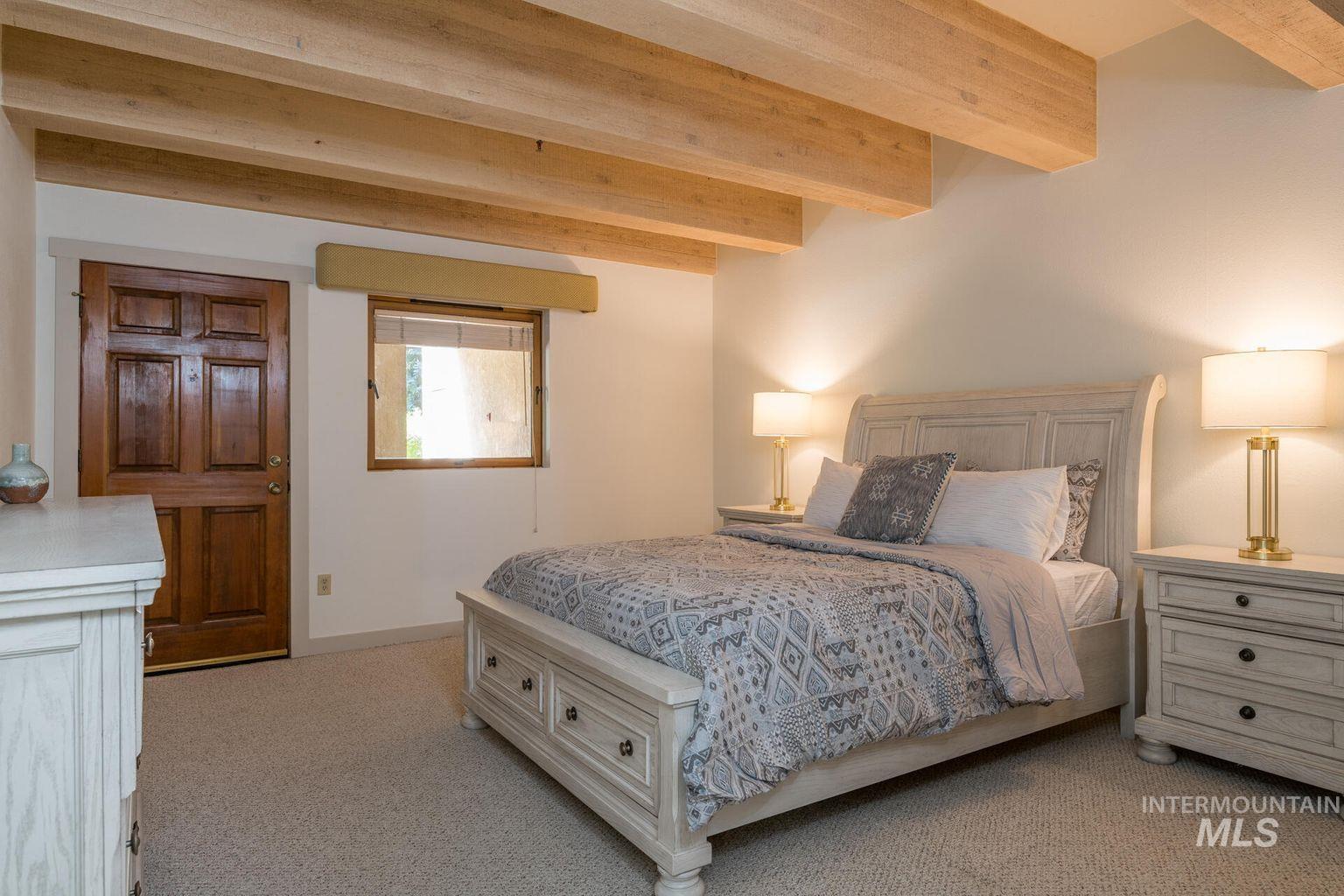 Bedroom featuring light carpet and beam ceiling
