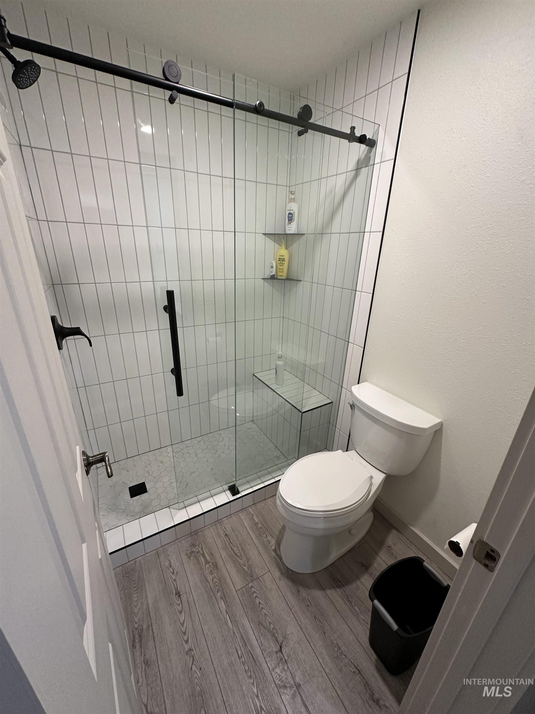 Full bathroom featuring a shower stall and wood finished floors