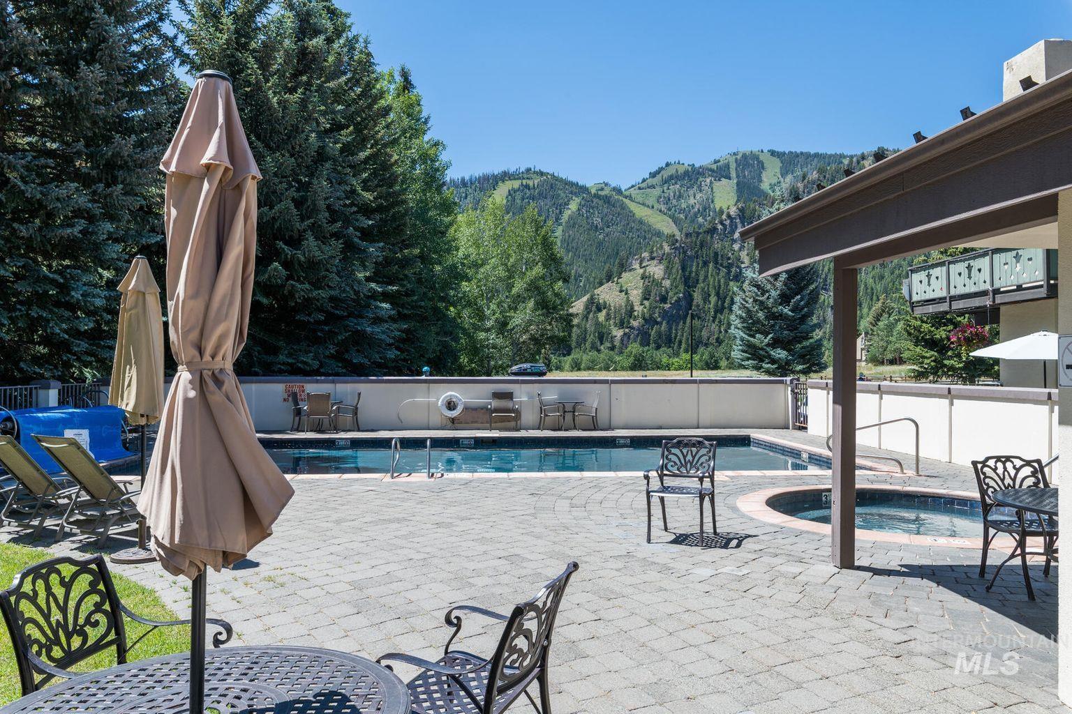 Community pool featuring a mountain view, a hot tub, and a patio area