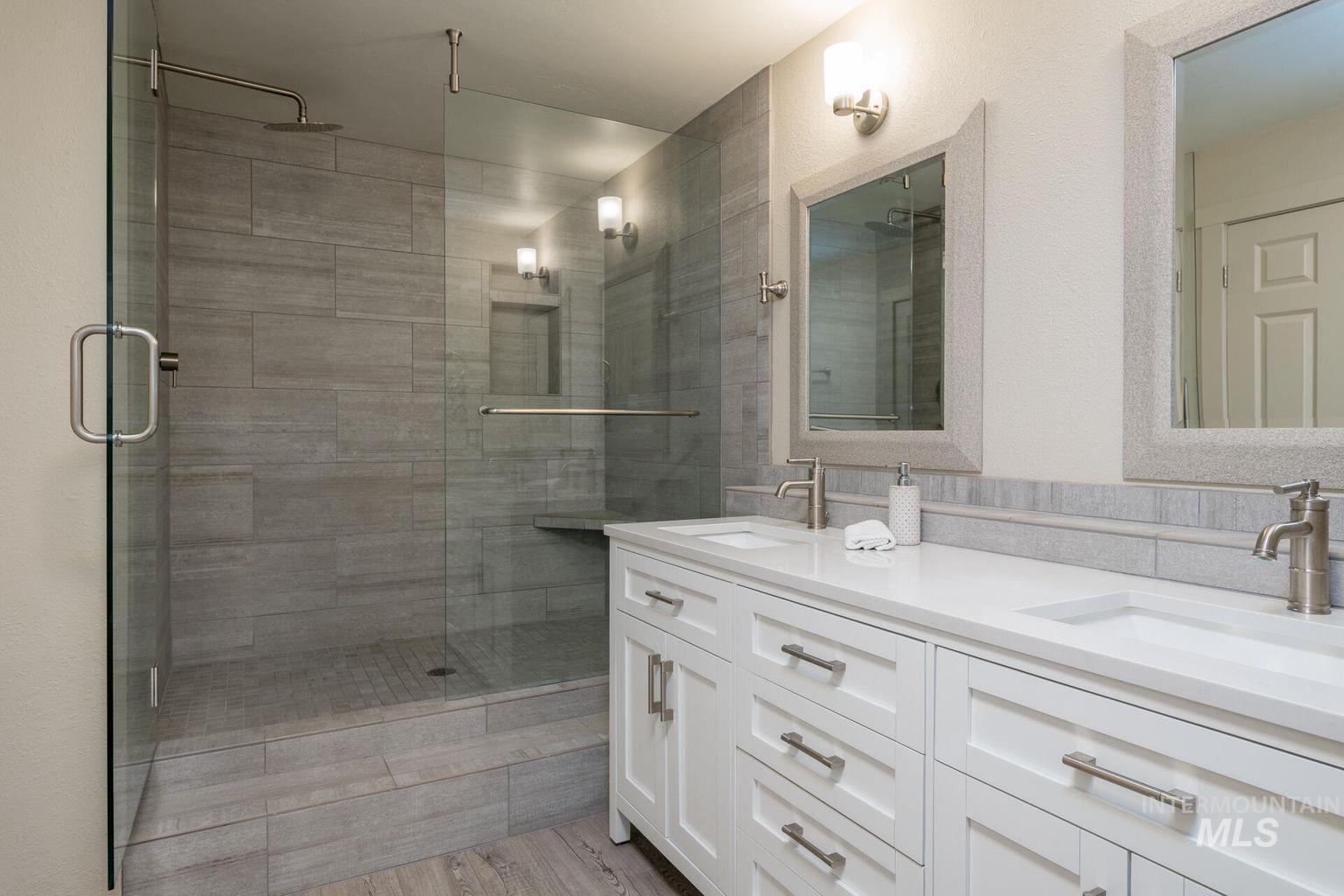 Bathroom with a stall shower, double vanity, and wood finished floors