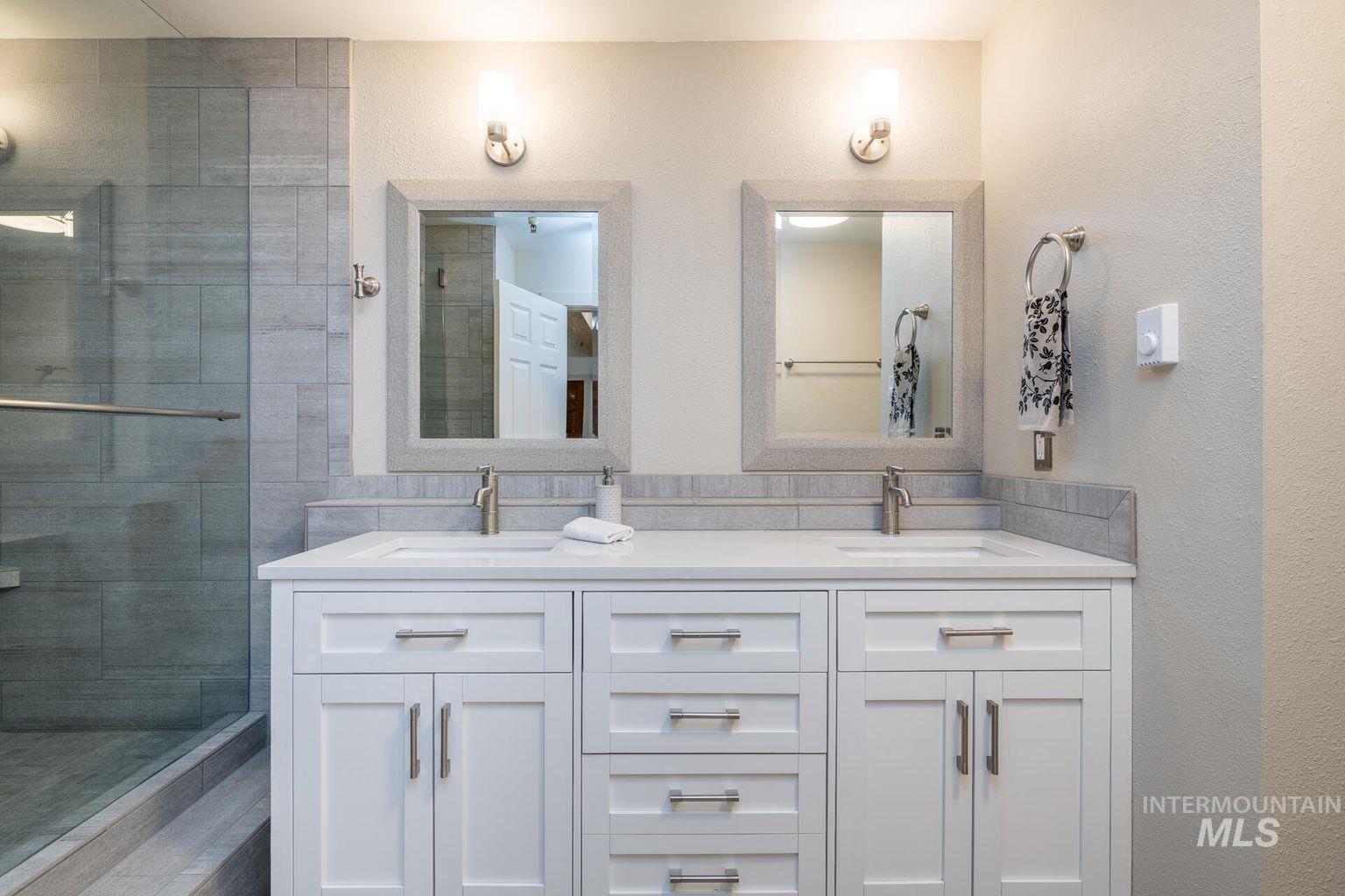 Full bath with double vanity and tiled shower