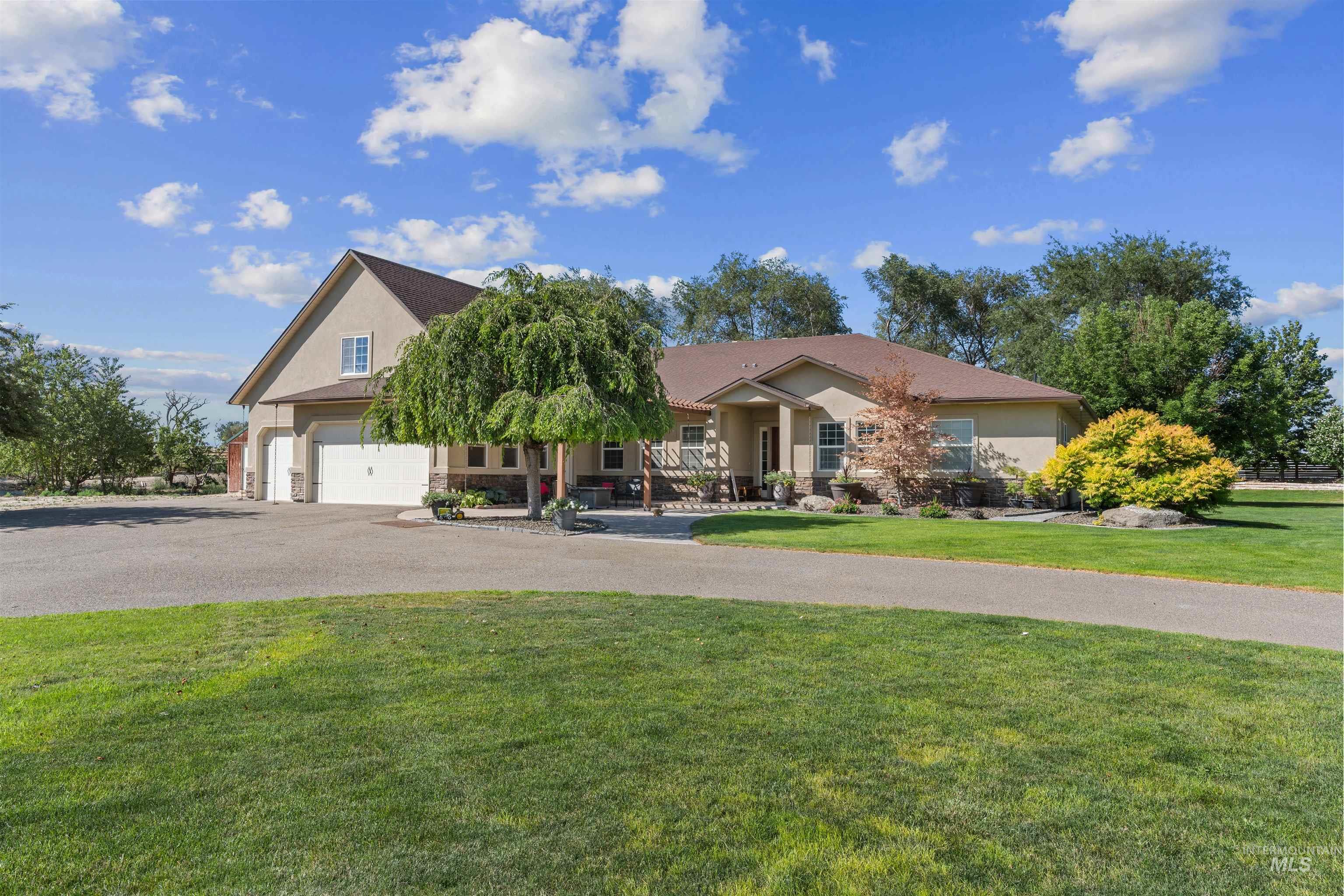 Obstructed view of property with stucco siding, a front yard, asphalt driveway, covered porch, and a garage