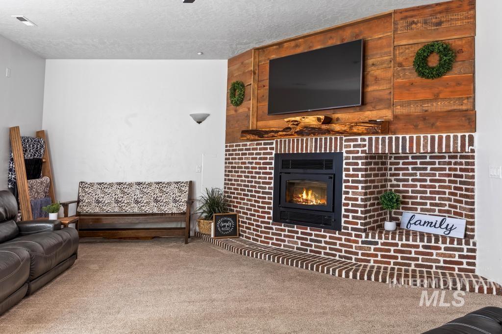 Carpeted living room with a glass covered fireplace and a textured ceiling