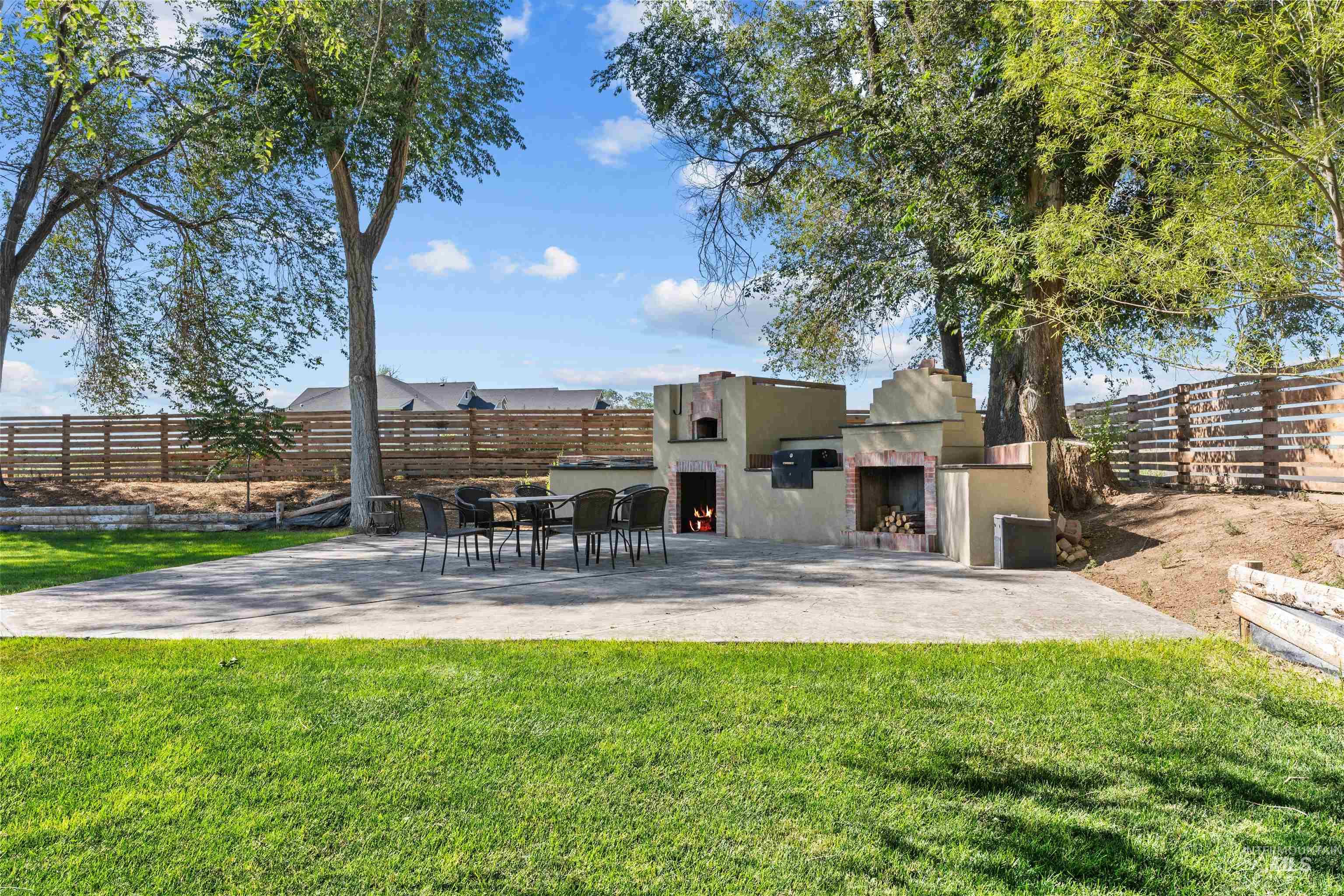 Fenced backyard with a warm lit fireplace and a patio