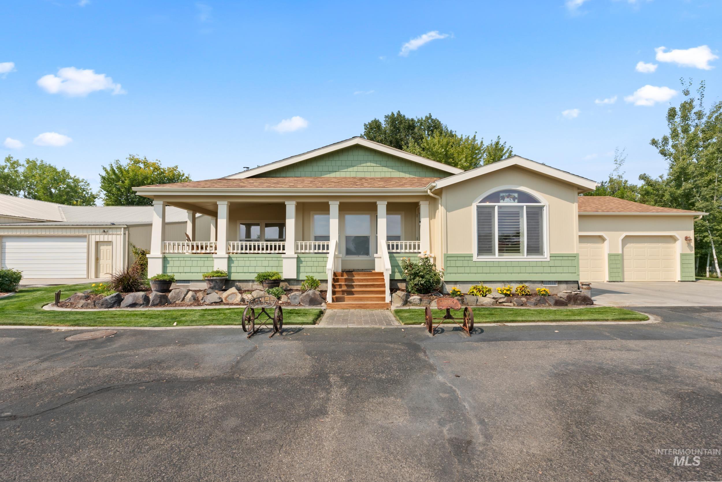 View of front of home with covered porch, driveway, an attached garage, and roof with shingles