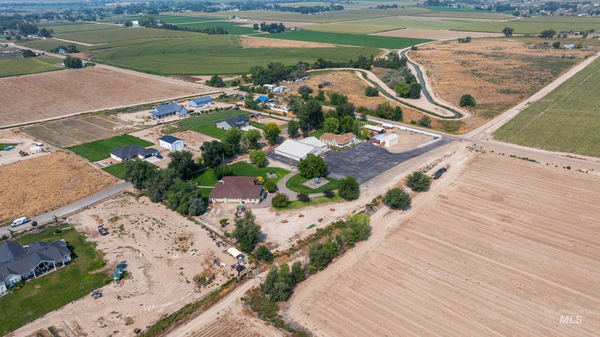 Aerial view of property and surrounding area featuring rural landscape and rows of crops