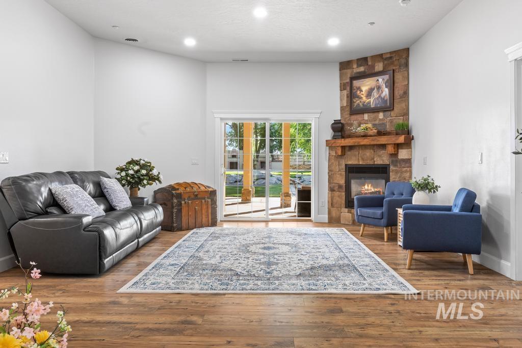 Living room with wood finished floors, a fireplace, and recessed lighting
