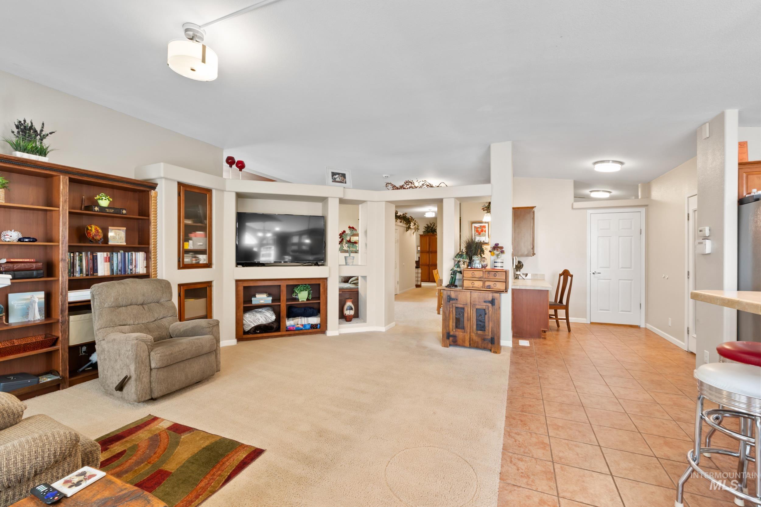 Living room with light tile patterned floors and light colored carpet