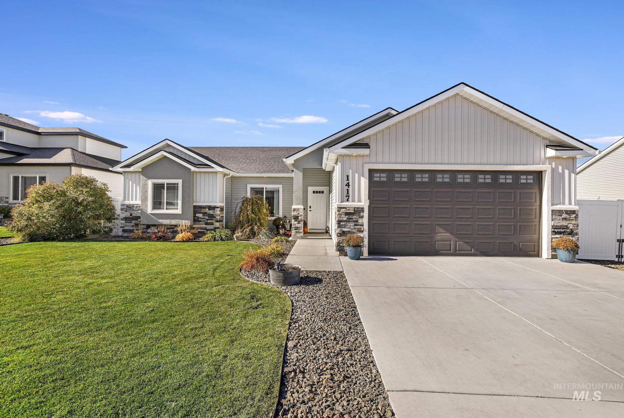 Craftsman-style house with stone siding, driveway, a front lawn, and a garage
