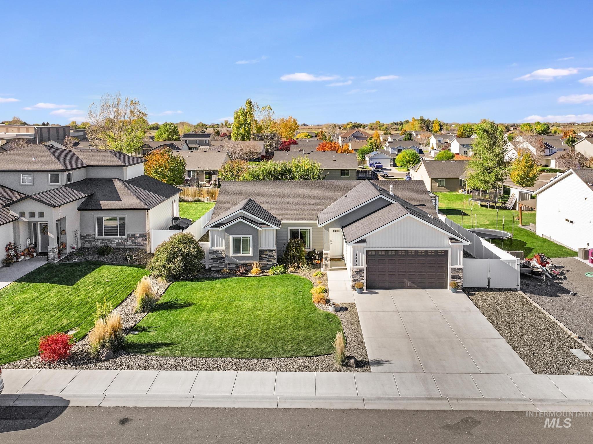 View of front of home featuring stone siding, concrete driveway, a garage, and a residential view