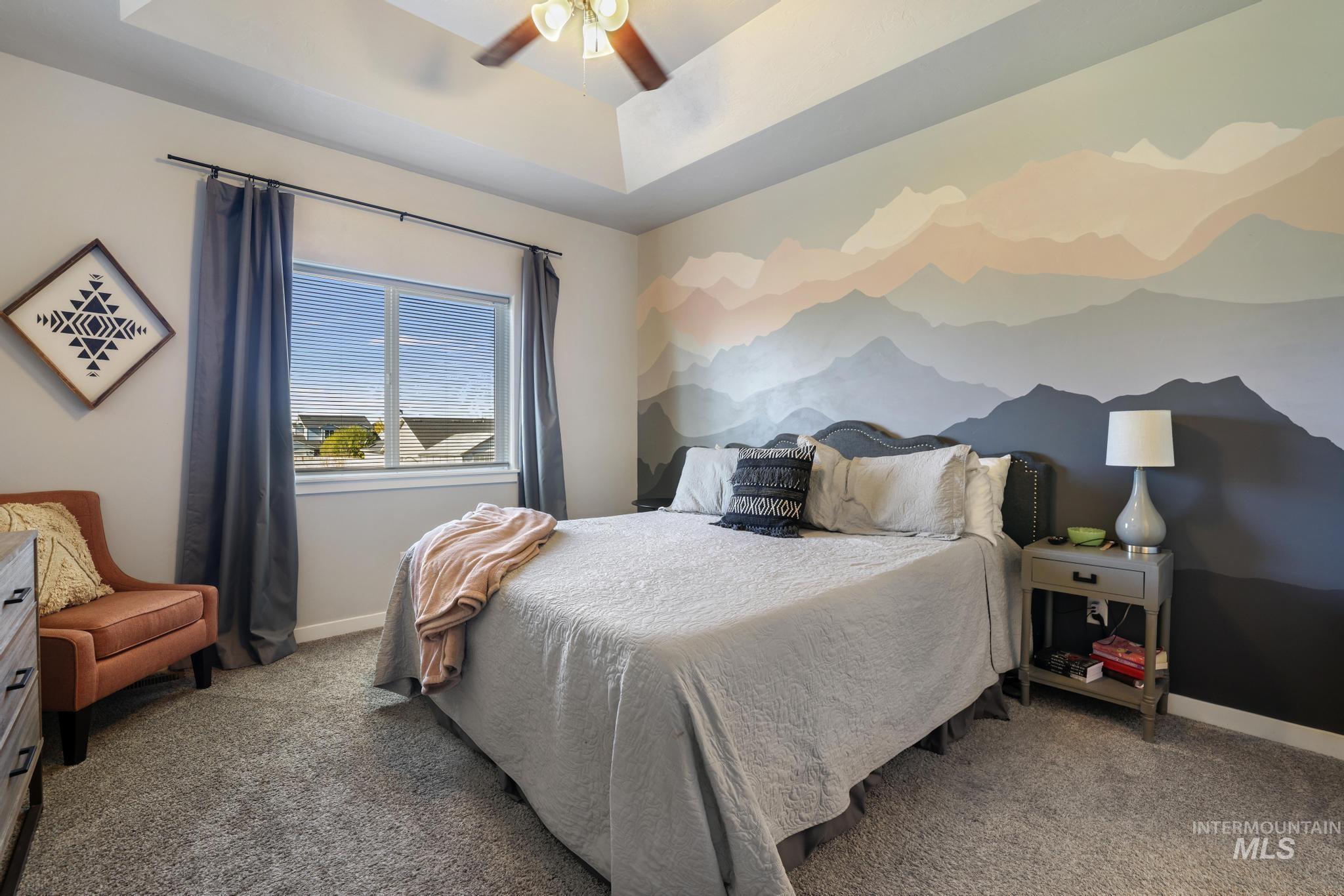 Bedroom featuring a raised ceiling, carpet, and a ceiling fan
