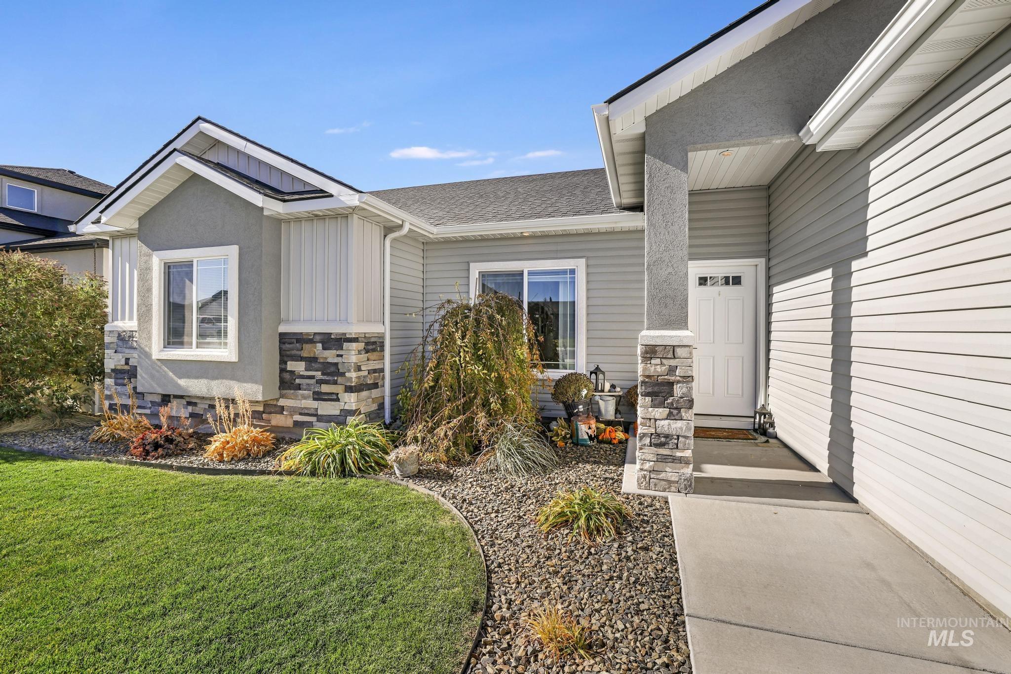 Doorway to property with stone siding, a yard, and roof with shingles
