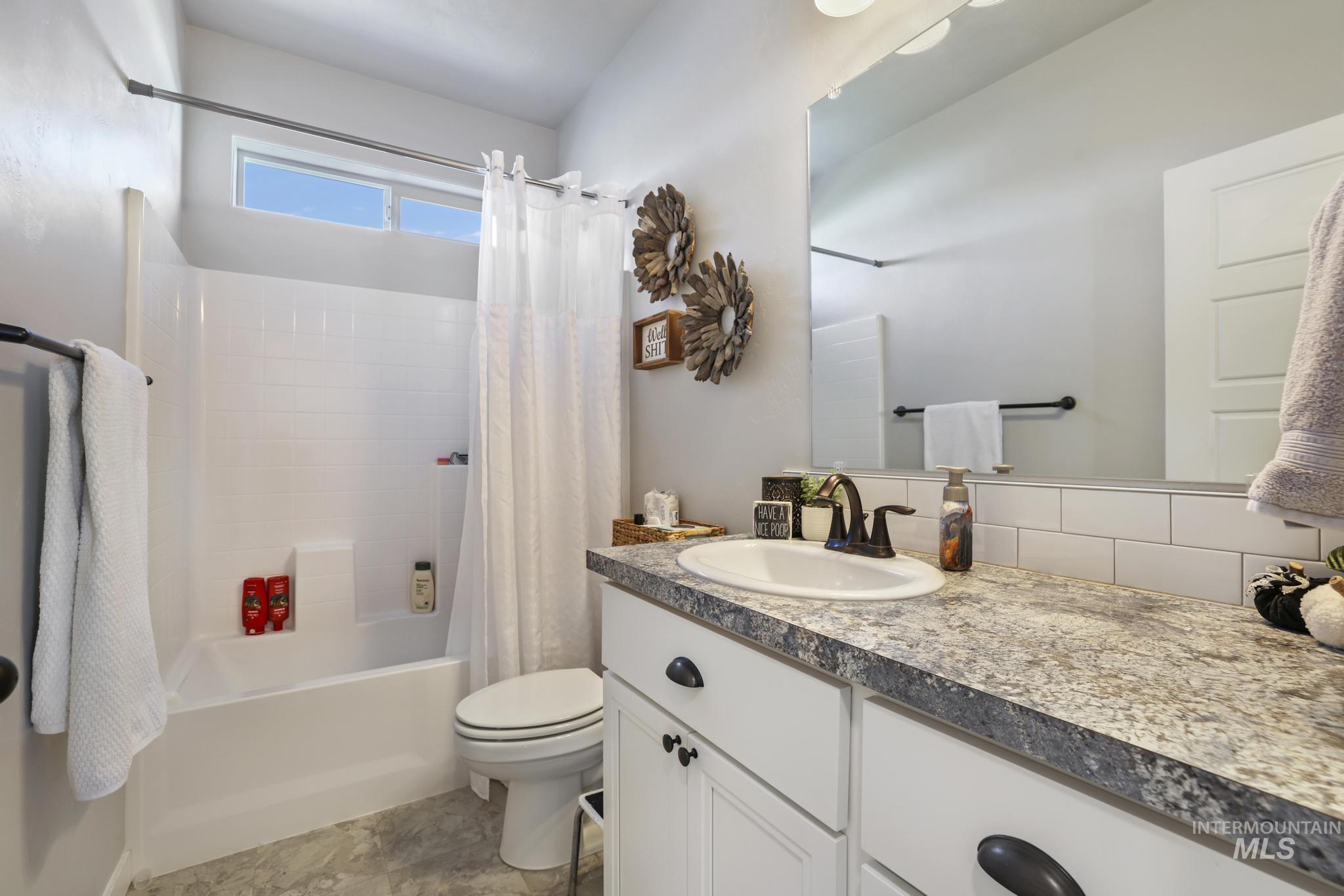 Bathroom with shower / bath combo, vanity, and tasteful backsplash