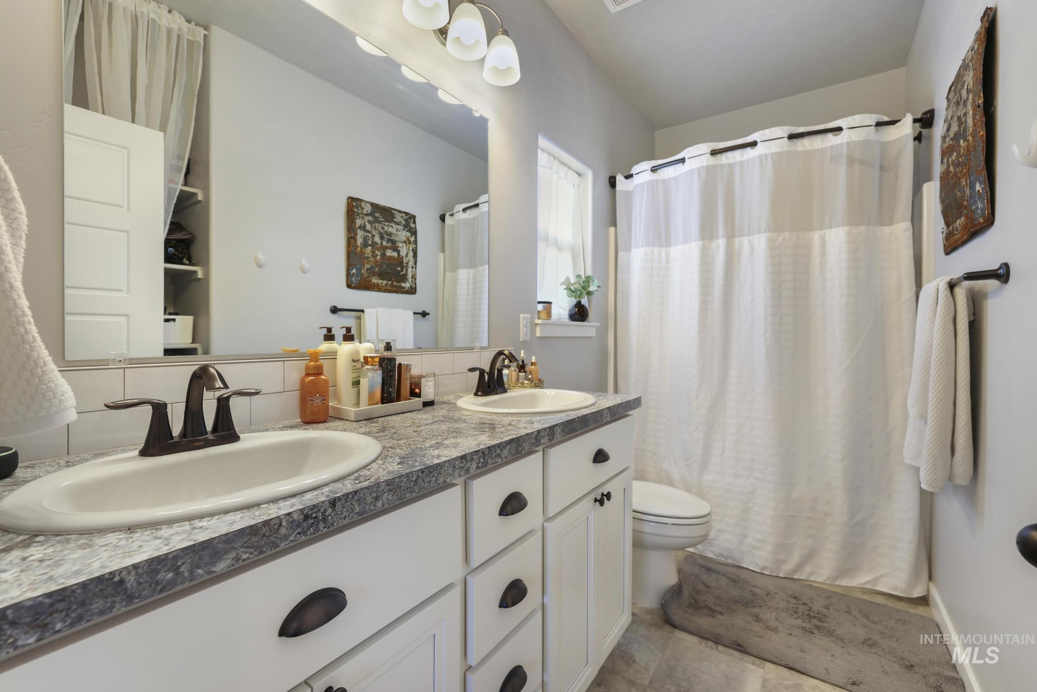Full bathroom with double vanity and shower / bath combination with curtain