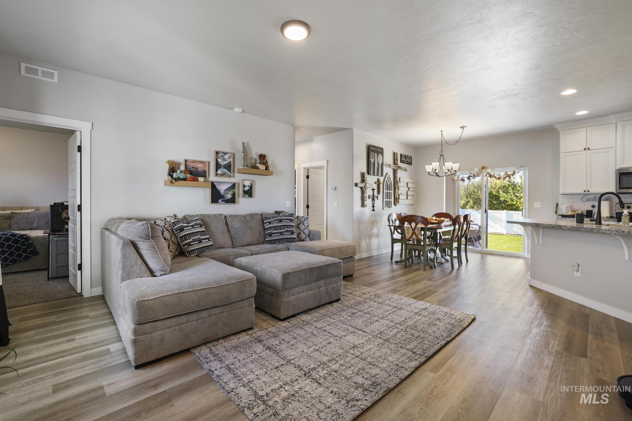 Living area featuring dark wood-type flooring, recessed lighting, and a chandelier