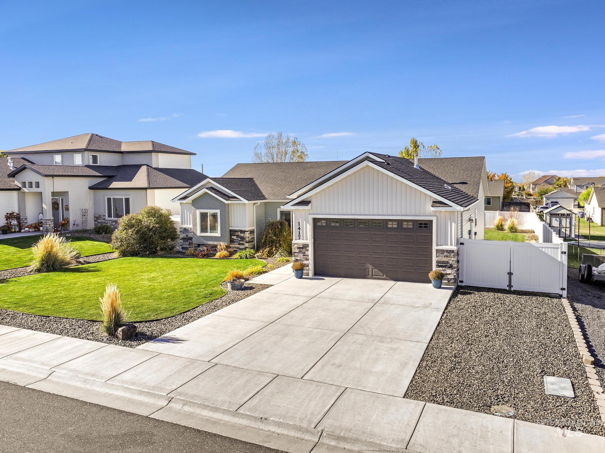 View of front facade with stone siding, a gate, concrete driveway, and an attached garage