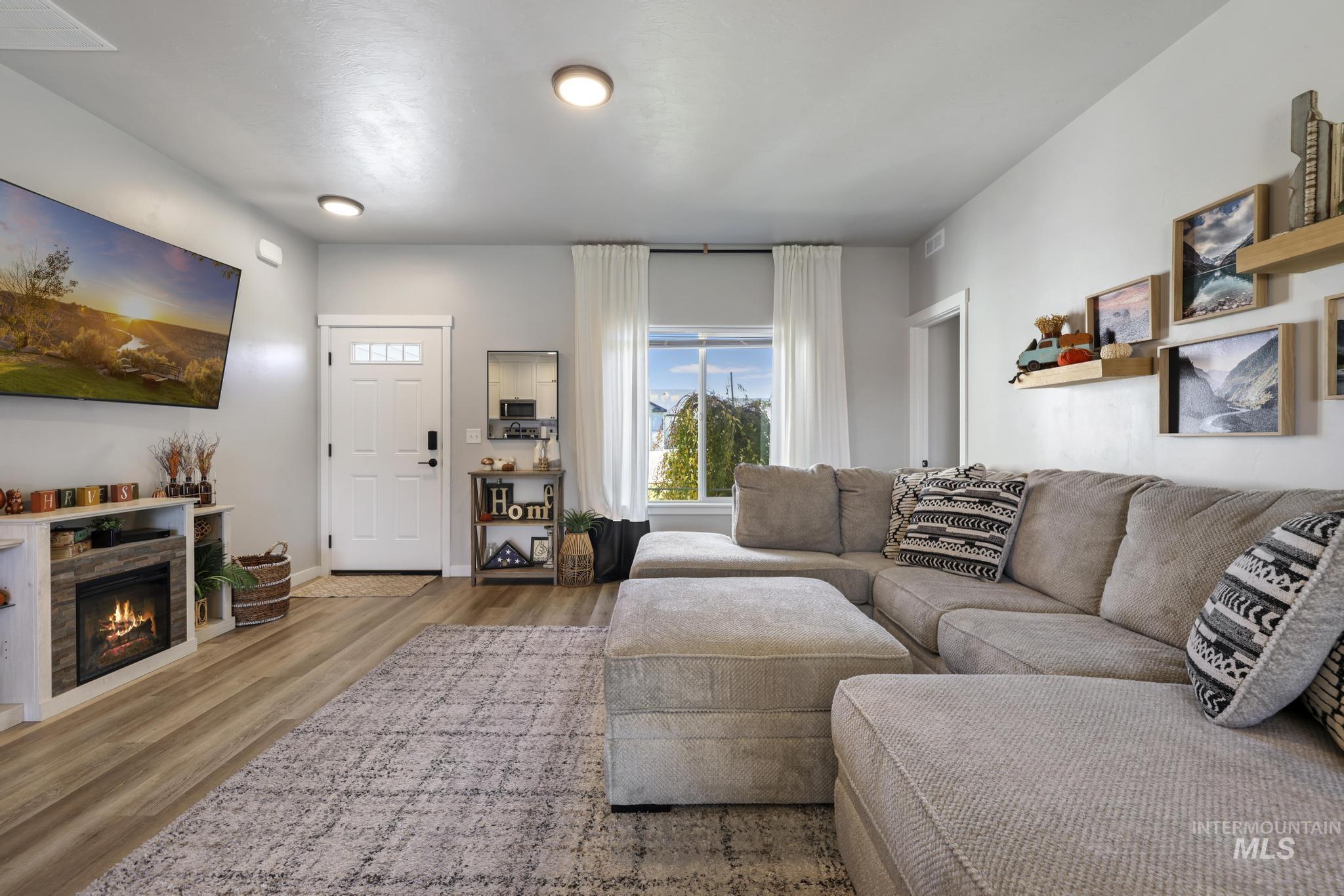Living room with wood finished floors and a lit fireplace