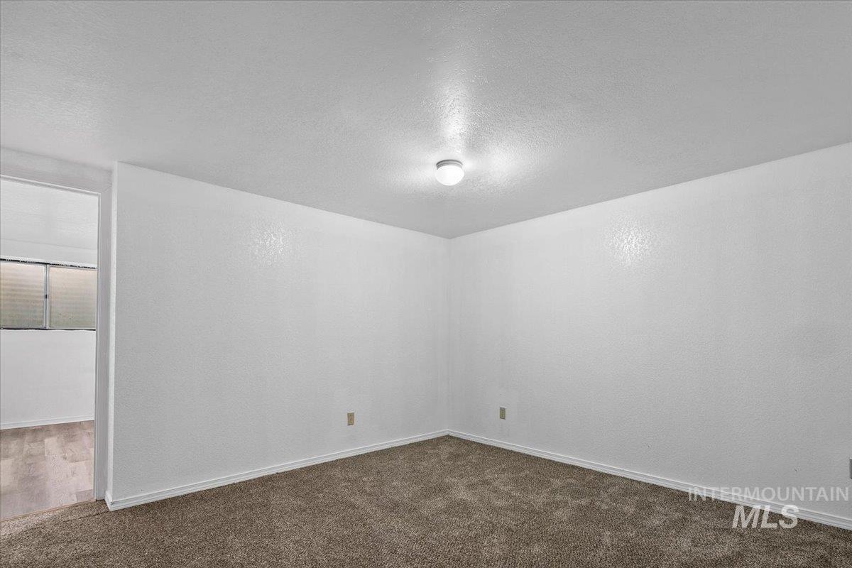 Spare room with a textured ceiling and dark colored carpet