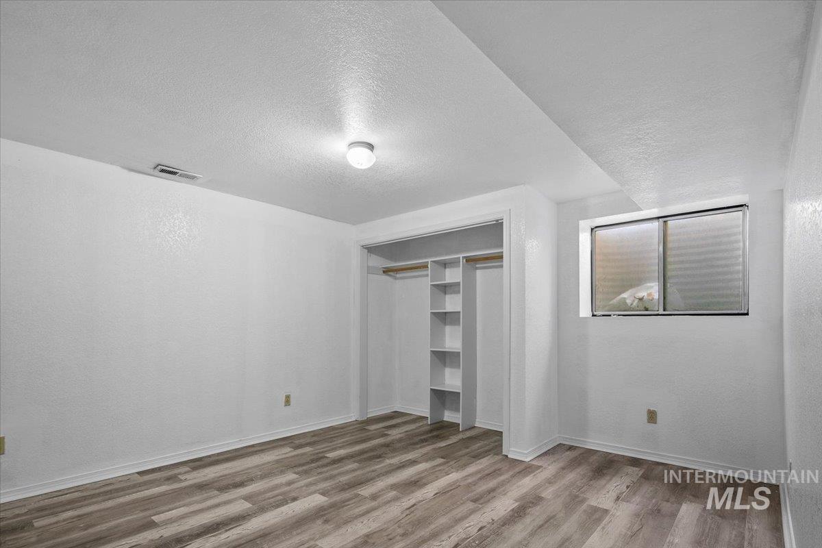 Unfurnished bedroom featuring a textured ceiling, light wood-style floors, and a closet