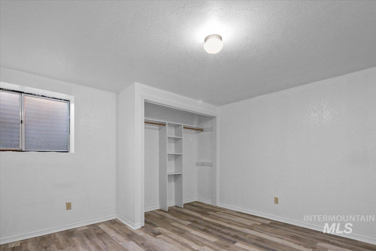 Unfurnished bedroom featuring wood finished floors, a textured ceiling, and a closet