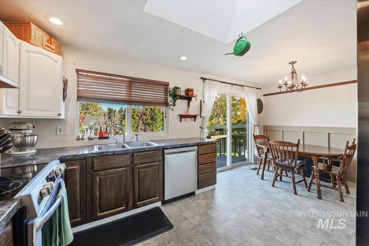 Kitchen with stainless steel appliances, dark brown cabinets, recessed lighting, a skylight, and a chandelier