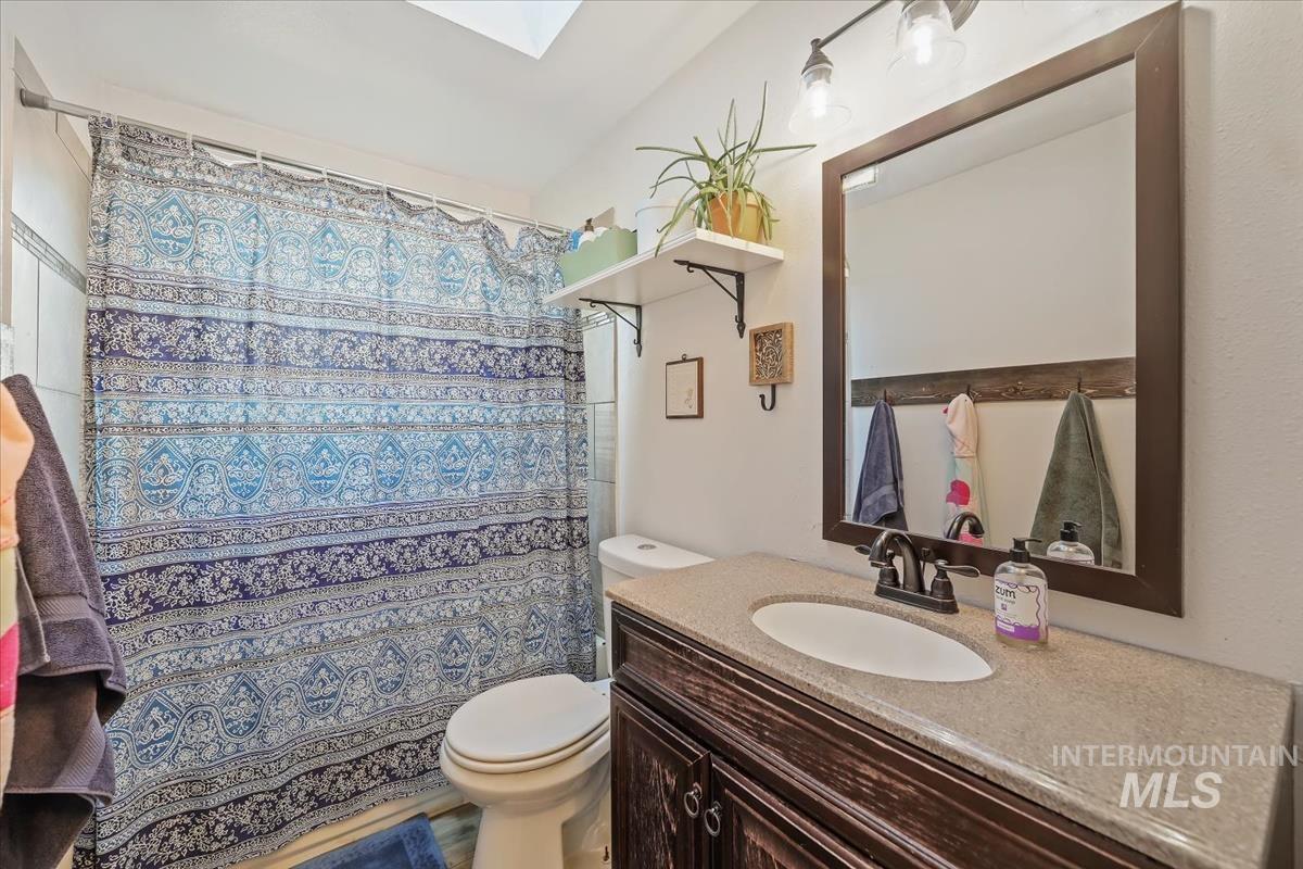 Full bathroom with a skylight, a shower with shower curtain, and vanity