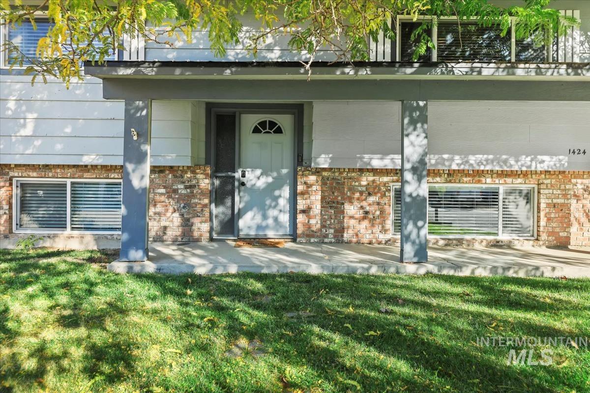 Entrance to property featuring brick siding and a yard