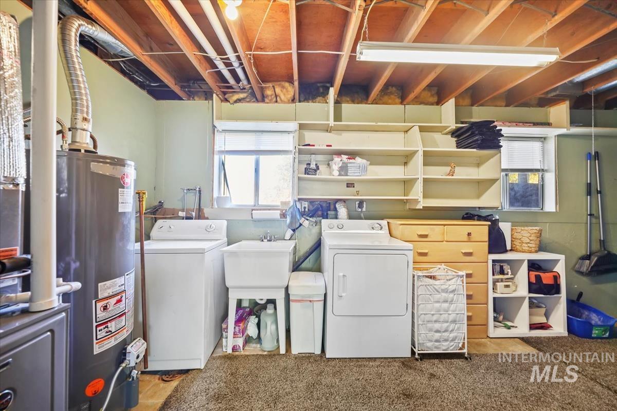 Laundry area featuring gas water heater, washing machine and clothes dryer, and light carpet