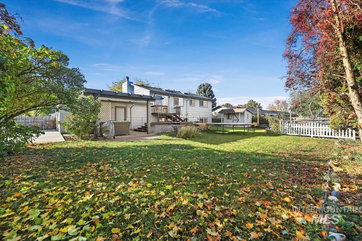 Back of property with a trampoline, a fenced backyard, a deck, and a chimney