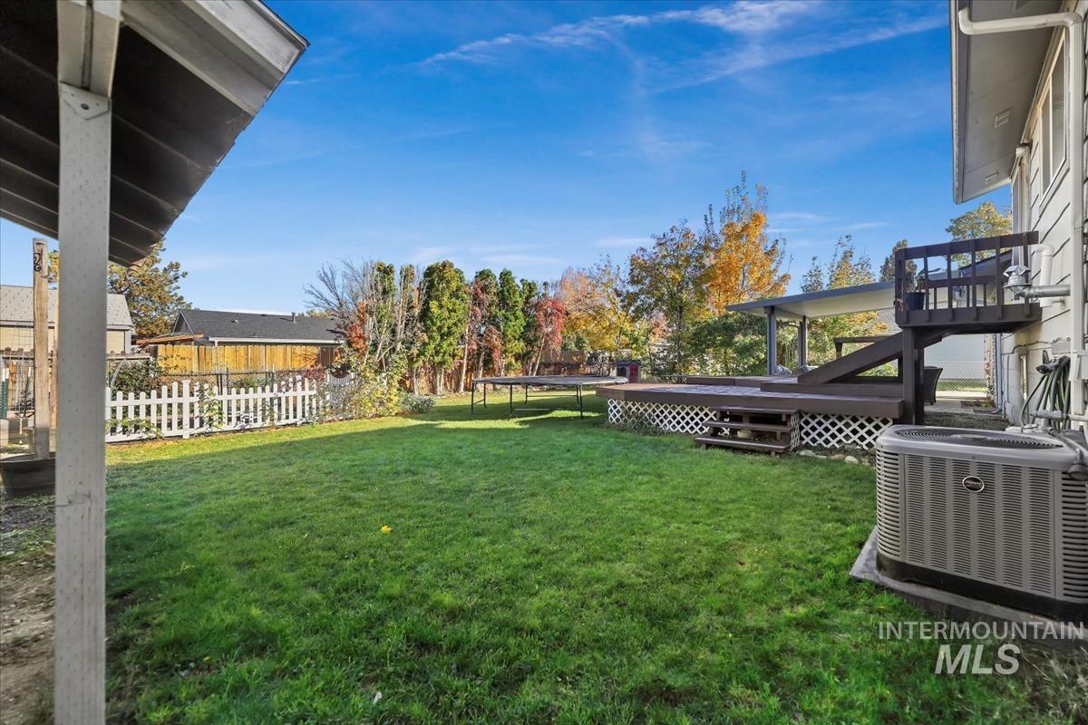 Fenced backyard with a trampoline and a deck