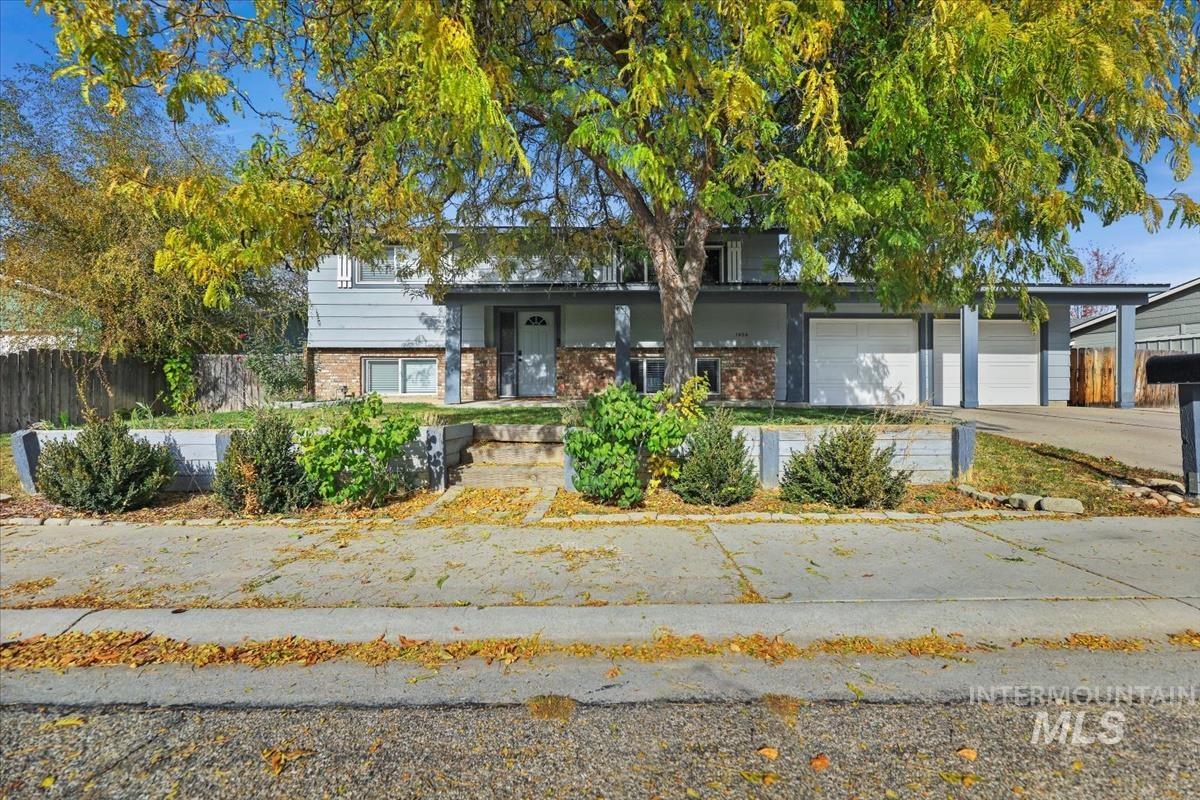 View of front of property featuring brick siding, covered porch, concrete driveway, and an attached garage