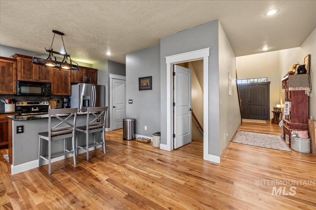 Kitchen featuring a kitchen breakfast bar, light wood-style floors, a kitchen island, pendant lighting, and a textured ceiling